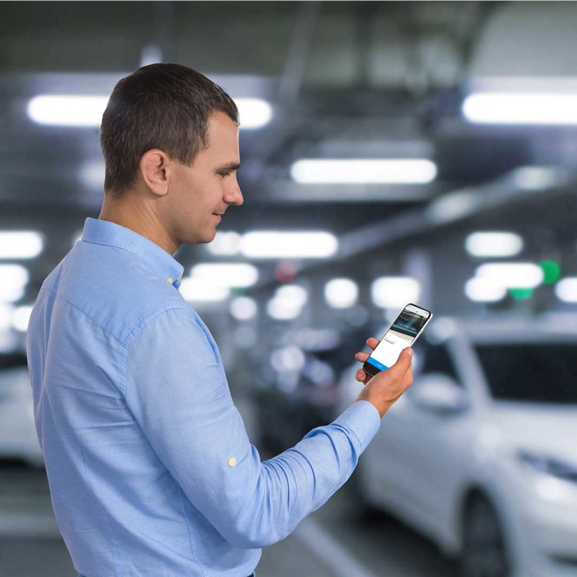 Man holding a phone with AI-powered VIN scanning technology on the screen with cars in the background