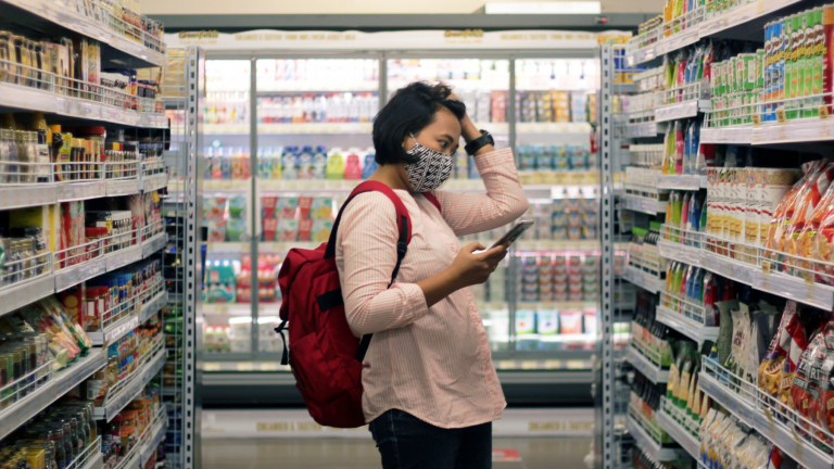 Woman shopping in a grocery store with her phone