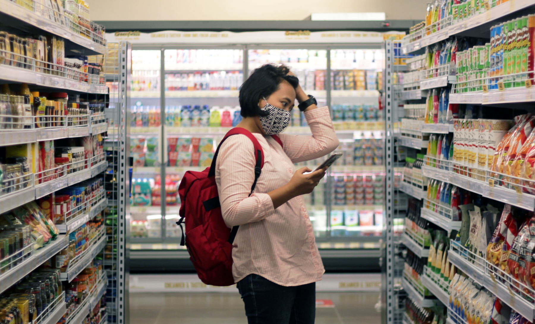 Woman shopping in a grocery store with her phone