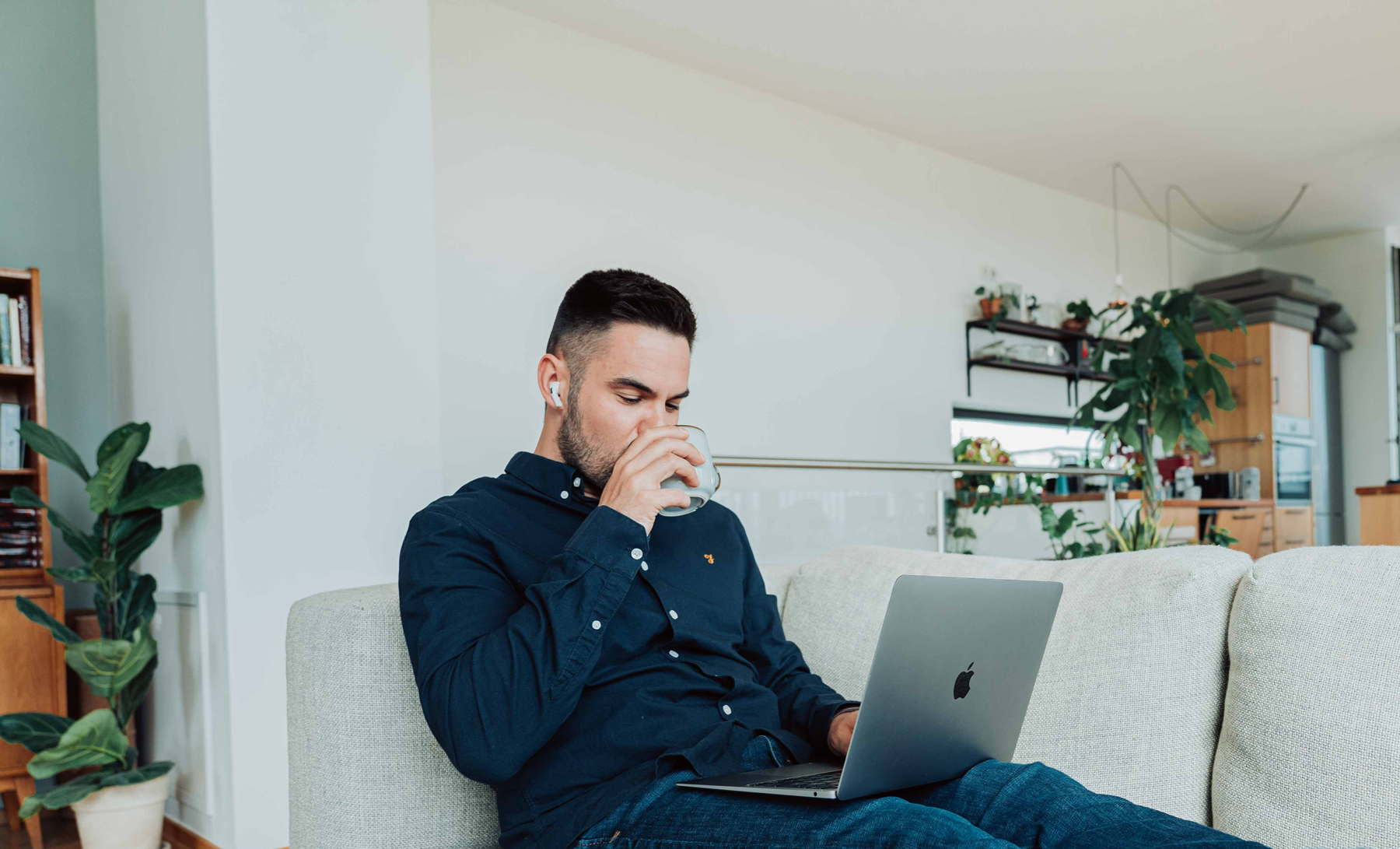 man sitting in a couch, drinking water while using a computer