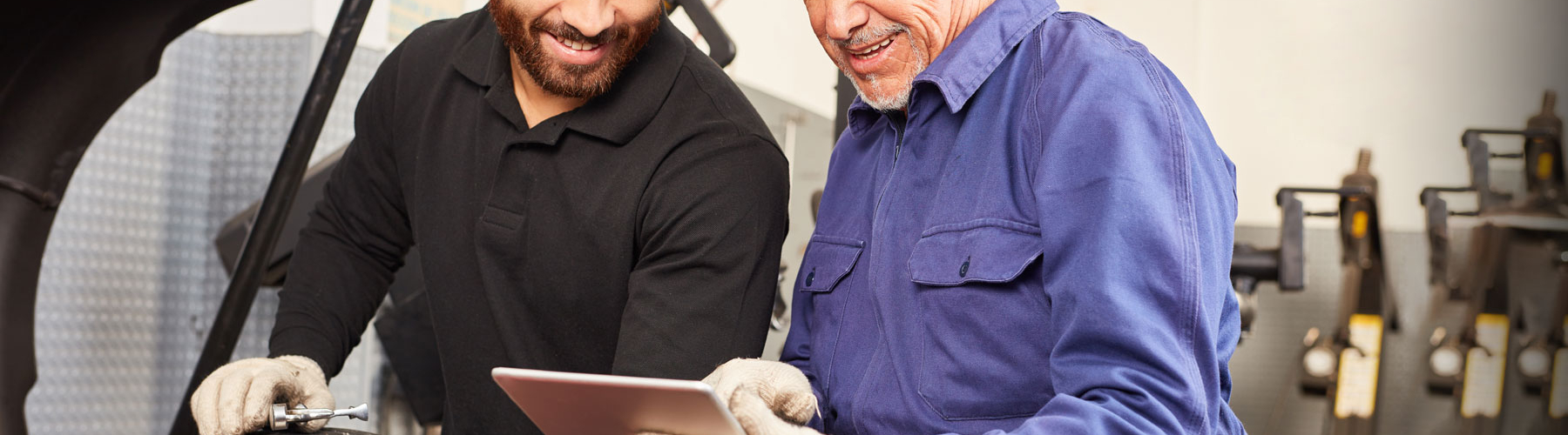 two tire technicians checking at something on a tablet
