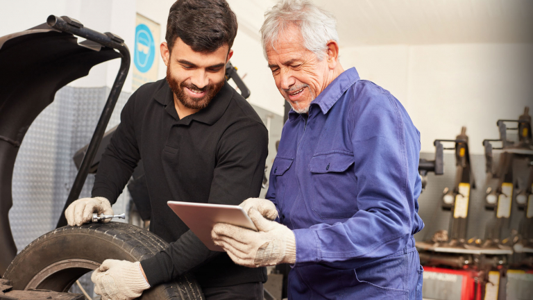 two tire technicians checking at something on a tablet