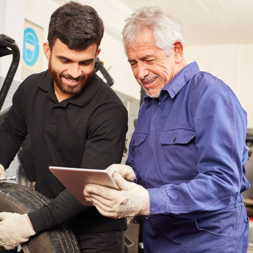 two tire technicians checking at something on a tablet