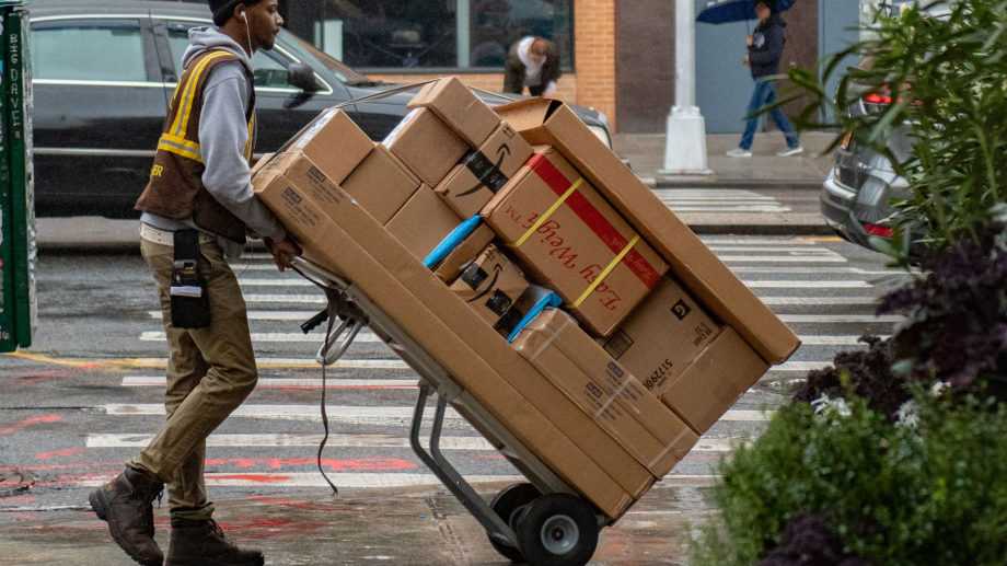 man delivering multiple parcels in a city