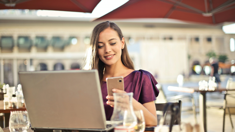 Woman sitting in a cafe with smartphone and laptop - Customer Satisfaction through Self Meter Reading