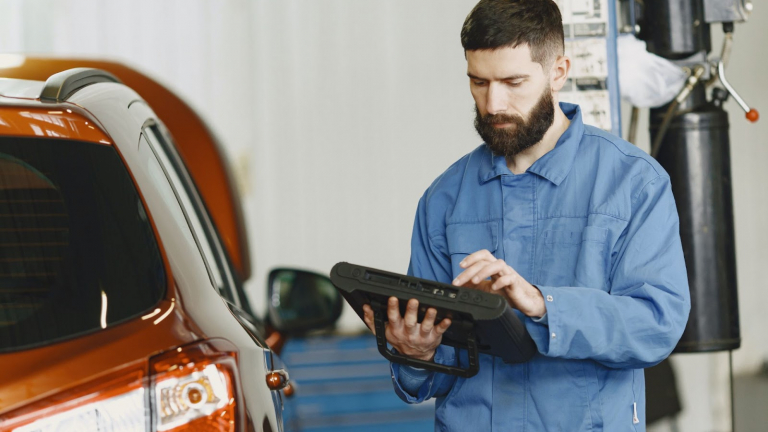 Man in Blue overall scans car with IPad