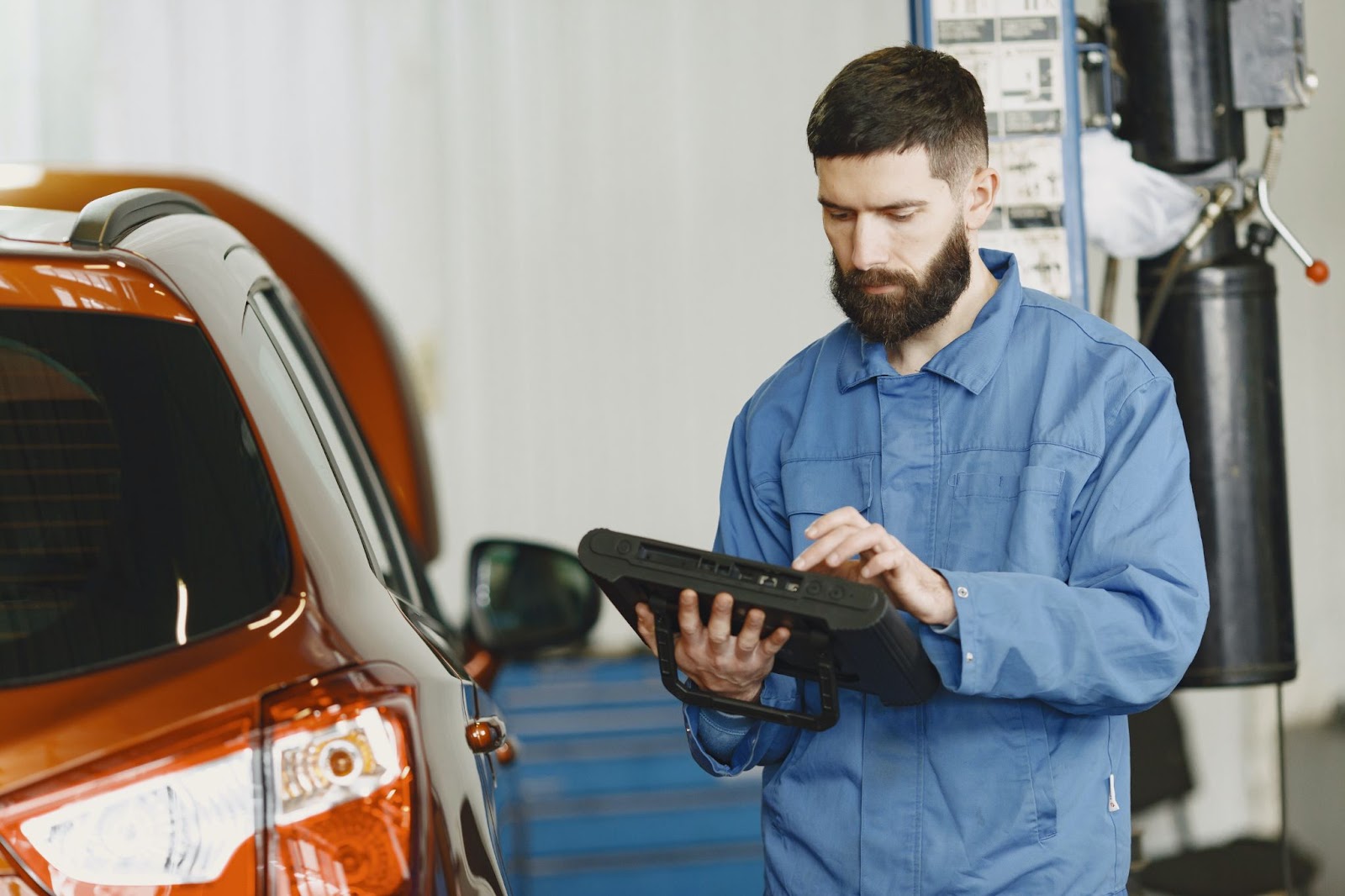Man in Blue overall scans car with IPad