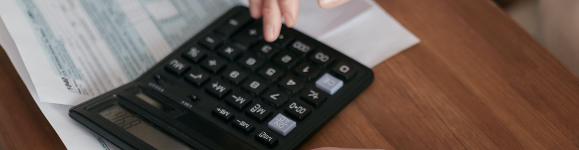 Woman calculating expenses with calculator over invoices