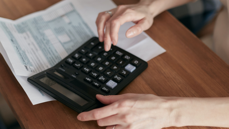 Woman calculating expenses with calculator over invoices