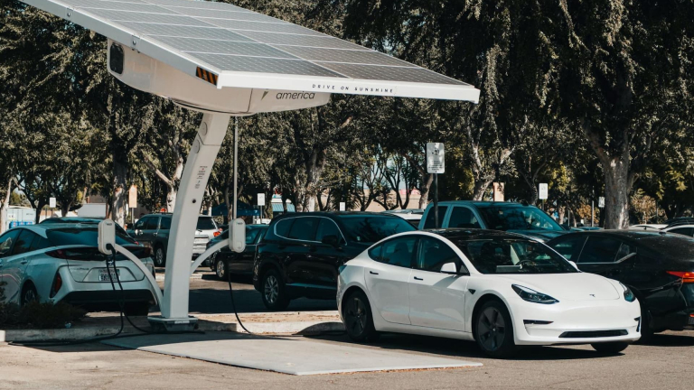 Tesla parking next to a charging station with solar panels