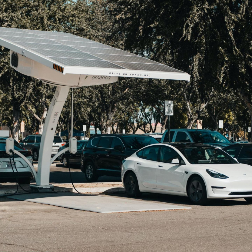 Tesla parking next to a charging station with solar panels