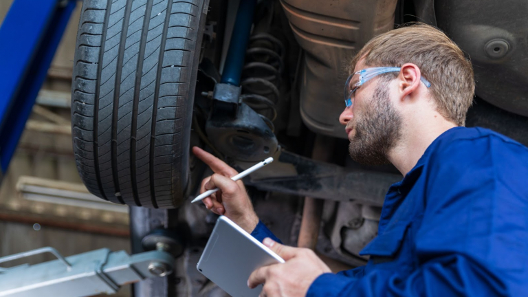 Mechanic looking at tire with tablet and pen