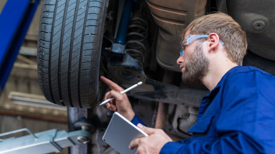 Mechanic looking at tire with tablet and pen