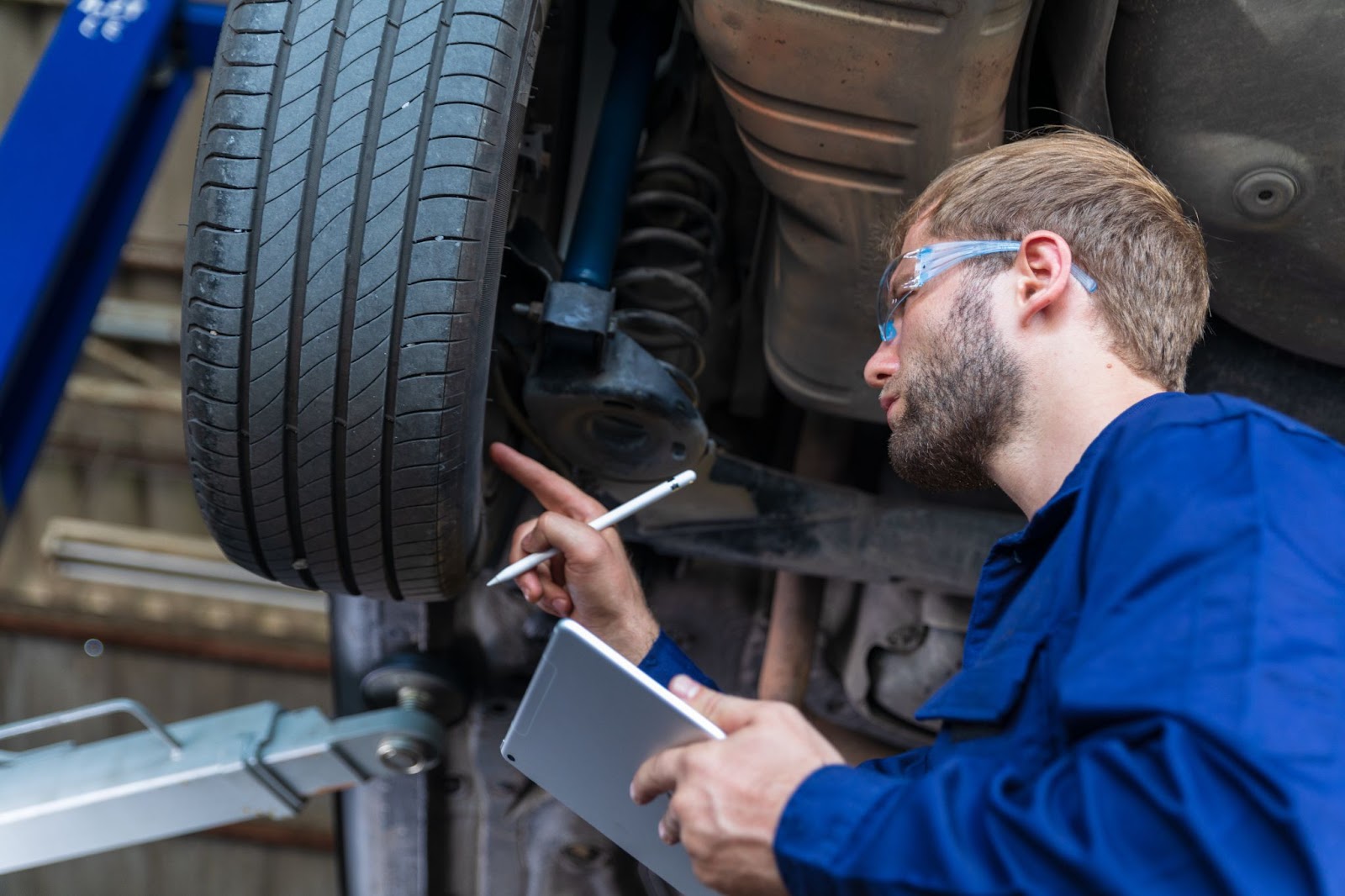 Mechanic looking at tire with tablet and pen