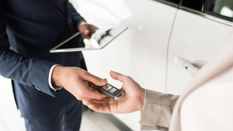 car dealer hands over vehicle keys to customer