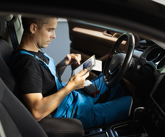 A technician in a car after having scanned an odometer with a tablet