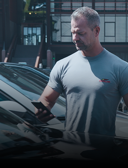 A man scanning a VIN on a windshield with a smartphone