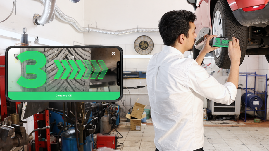 AI in real-world conditions. Man measures Tire Tread depth with AI-Powered mobile device.
