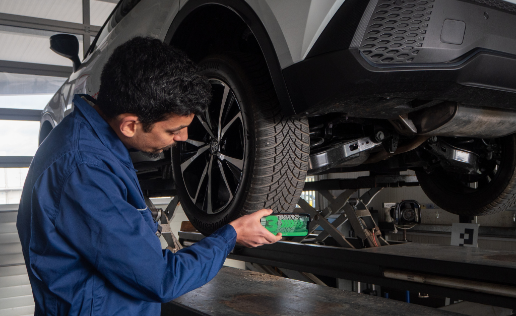 Automotive mechanic scanning tire tread with mobile device TireBuddy App